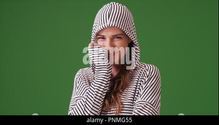 Portrait of woman wearing hoodie smiling at camera sur écran vert Banque D'Images