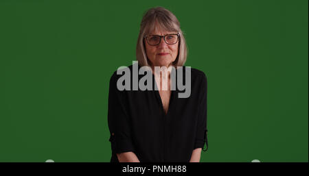 Sombre à la vieille femme de race blanche assise sur un écran vert Banque D'Images