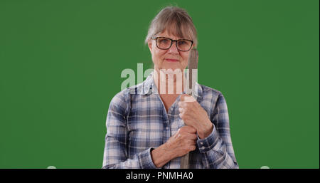 Vieille Femme posant avec l'outil agricole portrait sur écran vert Banque D'Images