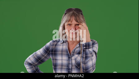 Old white woman posing for camera holding broom handle sur un écran vert Banque D'Images