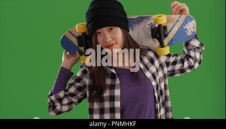 Hip young asian woman carrying skateboard sur l'épaulement de l'écran vert Banque D'Images