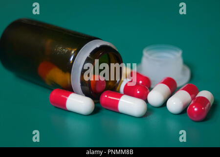 Les capsules de médicaments sur ordonnance dans une bouteille ouverte. Close-up of capsules sur fond vert Banque D'Images