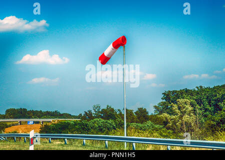 Chaussettes venteuses rouges et blanches sur le côté d'une interface avertissement sur route des véhicules à flancs hauts sur les vents latéraux dangereux Banque D'Images