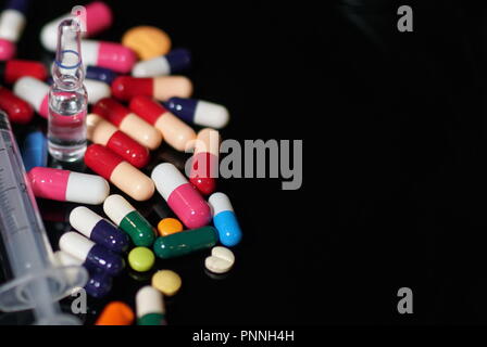 Les capsules de médicaments sur ordonnance dans une bouteille ouverte. La médecine, gélules, comprimés, d'injection, la seringue et l'aiguille. Close-up de différentes drogues Banque D'Images