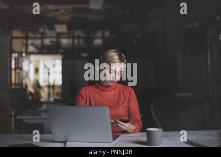 Les jeunes femelles adultes travaillant tard dans un bureau Banque D'Images
