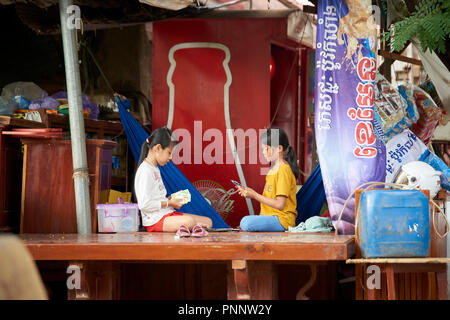 Deux jeunes filles jouant le jeu de cartes Uno dans une baraque entourée par l'image de fond, à Phnom Penh, Cambodge. Banque D'Images