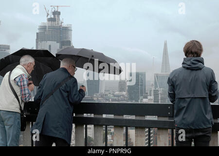 UK Weather.1 Yard Old Street, Old Street, Londres, Angleterre. Septembre 2018 22 les hommes détiennent deux parapluies dans la pluie en regardant la vue de Londres depuis le toit-terrasse de l'usine en col blanc au cours d'Open House de Londres. Credit : Judi Saunders/Alamy Live News Banque D'Images