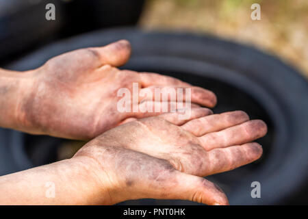 Gros plan du jeune homme les mains sales et le pneu à l'extérieur. Banque D'Images