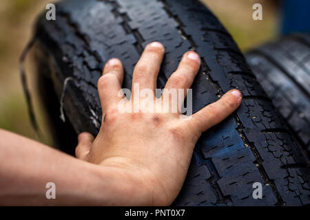 Gros plan du jeune homme les mains sales et le pneu à l'extérieur. Banque D'Images
