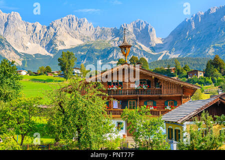 En bois typique maison alpine contre alpes contexte le pré vert à Going am Wilden Kaiser village aux beaux jours de l'été, Tyrol, Autriche Banque D'Images