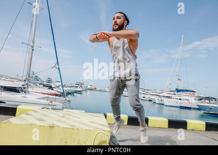 Athlète Fitness faisant sauter accroupi sur plyo-box de fortune sur mer pier Banque D'Images