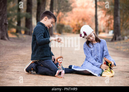 Garçon et fille jouant dans le parc avec des poupées de chiffon Banque D'Images