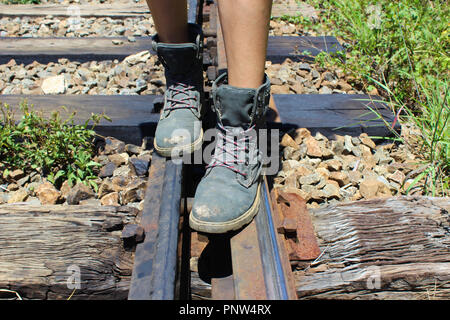 Personne marche avec des bottes de randonnée sur des voies de chemin de fer Banque D'Images