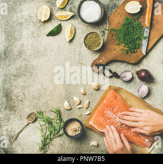 Femme mains cuisine du saumon salé filet de poisson sur la table gris Banque D'Images