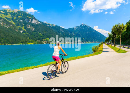 Jeune femme en vélo le long du lac Achensee Pertisau en ville, Tirol, Autriche Banque D'Images