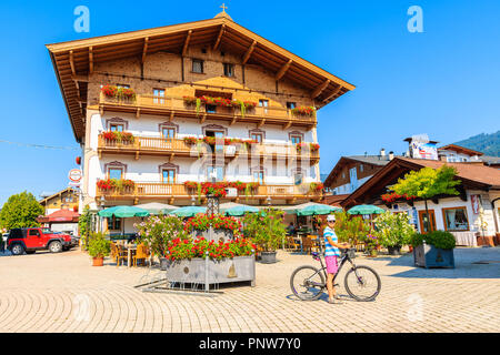 La ville de Kirchberg in Tirol, AUTRICHE - Aug 3, 2018 : young woman cyclist en face de chambre sur rue à Kirchberg in Tirol ville en été. Il est popula Banque D'Images