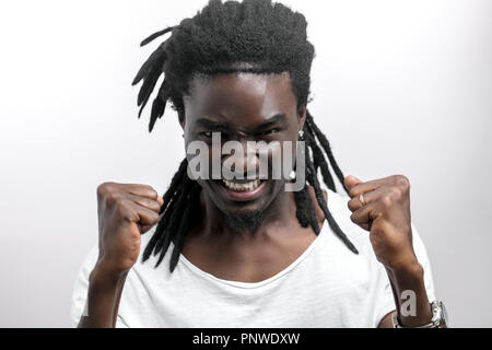 Jeune homme africain hurlant avec des dreadlocks isolés sur fond blanc. À la caméra. Banque D'Images
