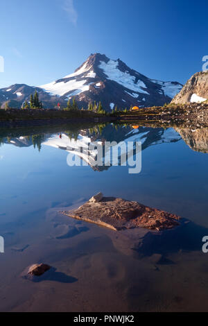 Randonneur et tente avec Mount Jefferson se reflétant dans un lac près de l'arrière-pays de l'Oregon Soeurs Banque D'Images