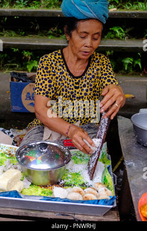 Une vieille dame la préparation de bonbons à un marché à Bali, Indonésie Banque D'Images