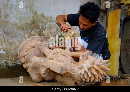 Un jeune homme fait un balinais de sculpture sur bois traditionnelle d'un dragon Banque D'Images