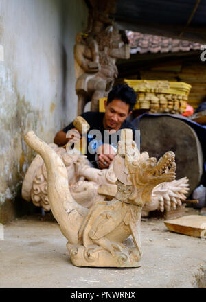 Un jeune homme fait un balinais de sculpture sur bois traditionnelle d'un dragon Banque D'Images