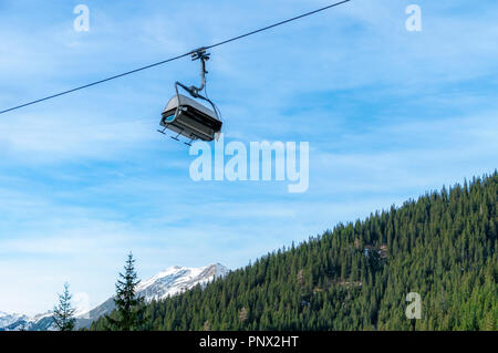 Télésiège de ski moderne fonctionnant sur un câble, plus evergreen forêt de sapins, dans les Alpes autrichiennes, montagnes, dans la région de Ehrwald, Autriche, lors d'une journée ensoleillée du mois de décembre. Banque D'Images