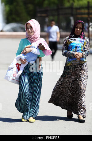 Tachkent, Ouzbékistan - 01 mai 2017 : l'Ouzbek woman wear repéré portant son enfant et marcher avec une autre femme dans le marché Chorsu Banque D'Images