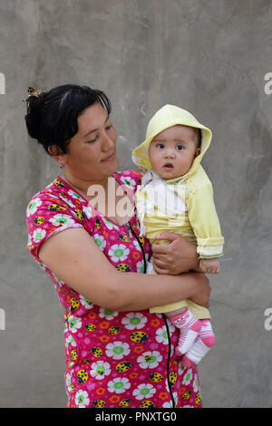 Tachkent, Ouzbékistan - Mai 08, 2017 : femme ouzbek se tenant son enfant dans la main. Banque D'Images