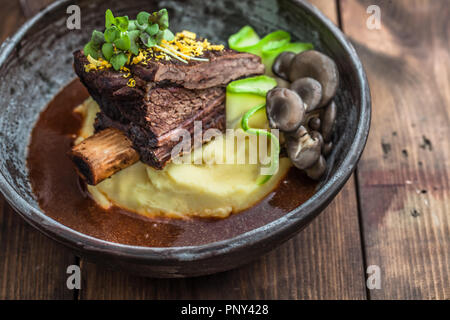 Bouts de côte de bœuf mijoté lentement avec des pommes de terre, champignons et sauce. Banque D'Images