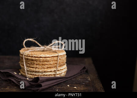 Gaufres néerlandais stroopwafel, avec le caramel. Pile de gaufres néerlandais traditionnels faits maison sur table rustique foncé. Banque D'Images