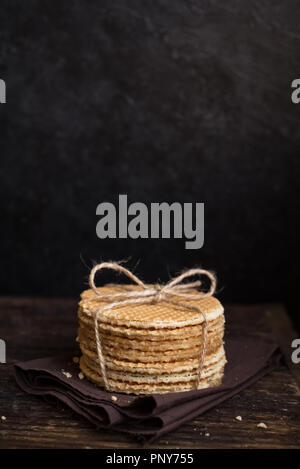 Gaufres néerlandais stroopwafel, avec le caramel. Pile de gaufres néerlandais traditionnels faits maison sur table rustique foncé. Banque D'Images