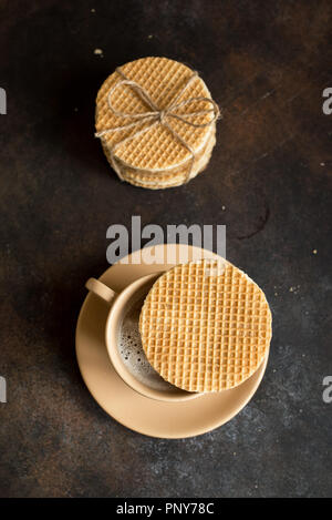 Gaufres néerlandais stroopwafel, de caramel et de boisson chaude. Gaufres néerlandais traditionnels faits maison sur table rustique foncé. Banque D'Images