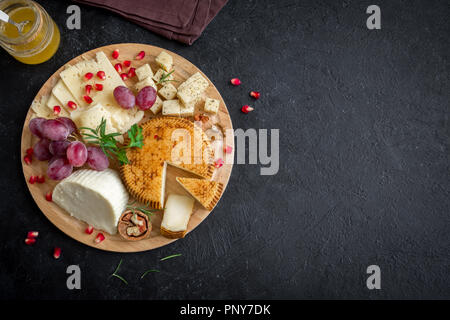 Assiette de fromage avec un assortiment de fromages, les raisins, les noix sur fond noir, copiez l'espace. Plateau de fruits et de fromage italien. Banque D'Images