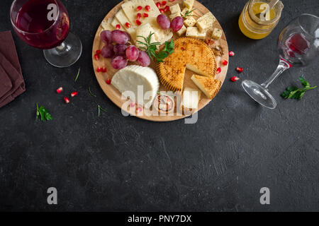 Assiette de fromage avec un assortiment de fromages, les raisins, les noix sur fond noir, copiez l'espace. Plateau de fruits et de fromage italien. Banque D'Images