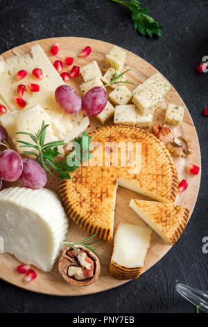 Assiette de fromage avec un assortiment de fromages, les raisins, les noix sur fond noir, copiez l'espace. Plateau de fruits et de fromage italien. Banque D'Images