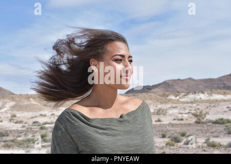 Mixed Race jeune fille dans le désert avec les cheveux au vent Banque D'Images