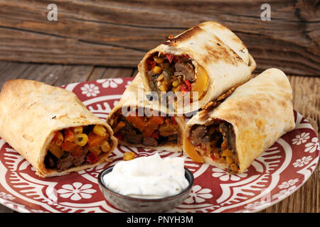 Burritos Wraps au boeuf et légumes sur fond de bois. Beef burrito, cuisine mexicaine. Banque D'Images