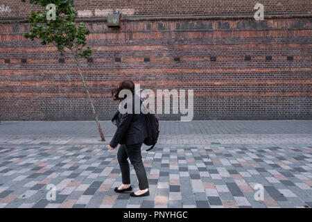 Une personne solitaire passe devant un arbre solitaire sur un jour de vent à Londres Banque D'Images