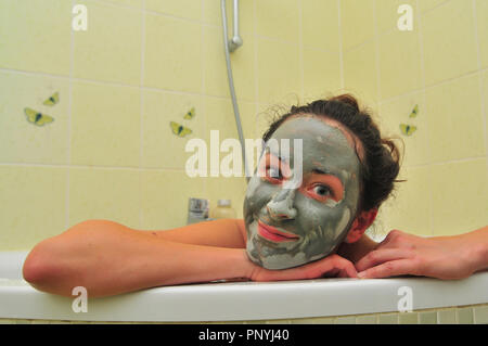 Visage de jeune femme avec un masque de boue dans la baignoire. Banque D'Images