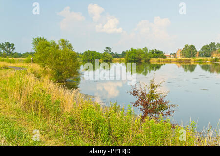 Teinté Orange puffy nuages reflétée dans un lac à St Louis Bellefontaine de conservation sur un après-midi d'été avec les orages isolés dans l'une Banque D'Images