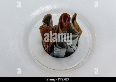 Les notes vers le bas un livre blanc de l'argent jeté signifiant plughole Banque D'Images