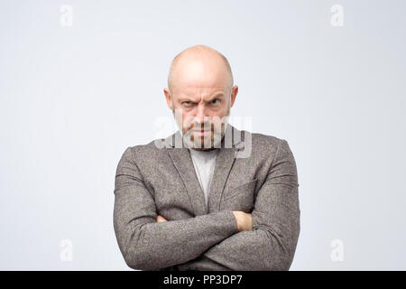 Portrait de l'offensé man in suit holding mains croisées sur la poitrine, à la recherche de dessous front Banque D'Images