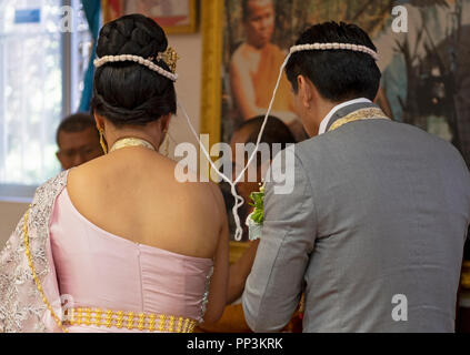 Une vue arrière de la mariée et le marié au cours d'une cérémonie de mariage bouddhiste. Leurs têtes sont attachés ensemble avec un fil sacré. Dans Elmhurst, Queens, New York. Banque D'Images