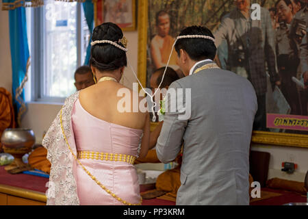 Une vue arrière de la mariée et le marié au cours d'une cérémonie de mariage bouddhiste. Leurs têtes sont attachés ensemble avec un fil sacré. Dans Elmhurst, Queens, New York. Banque D'Images