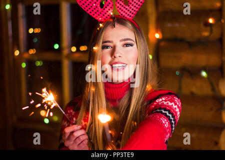 Belle fille avec Noël scintille dans une cabane en bois Banque D'Images