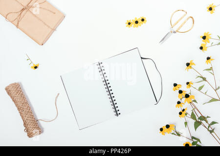 Fleuriste rustique avec télévision composition laïcs sketchbook vide dans le centre. Vue de dessus du blank notepad ouvert entouré de fleurs jaunes, ficelle, ciseaux et bro Banque D'Images