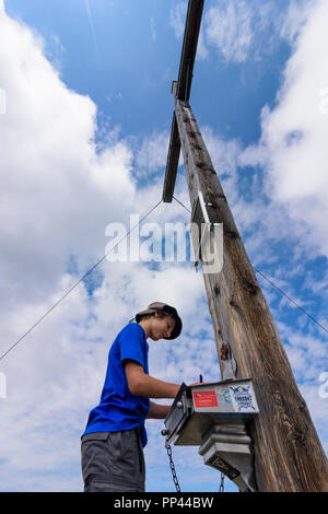 Randonneur Venet : Jeune homme garçon écrit dans sommet livre à mountain sommet Venet, Glanderspitze sommet cross, région TirolWest, Tirol, Tyrol, Autriche Banque D'Images