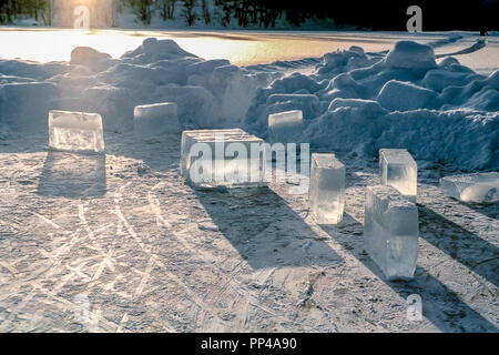 Gros cubes de glace sur un lac glacé avec de la neige et du soleil autour. Banque D'Images