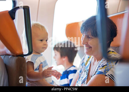 Grand-mère et bébé garçon, voyageant dans un train, aller sur un jorney ensemble, un frère assise à côté d'eux, profitant de la vue Banque D'Images