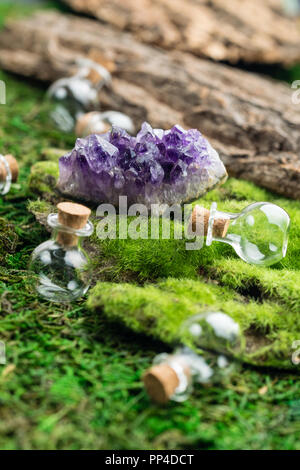 Fiole magique et pierre améthyste émeraude sur moss dans la forêt. Thème de l'Halloween. Banque D'Images